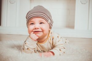 Bebé sonriendo con gorro y fondo crema