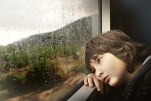 niño en la ventana mirando la lluvia